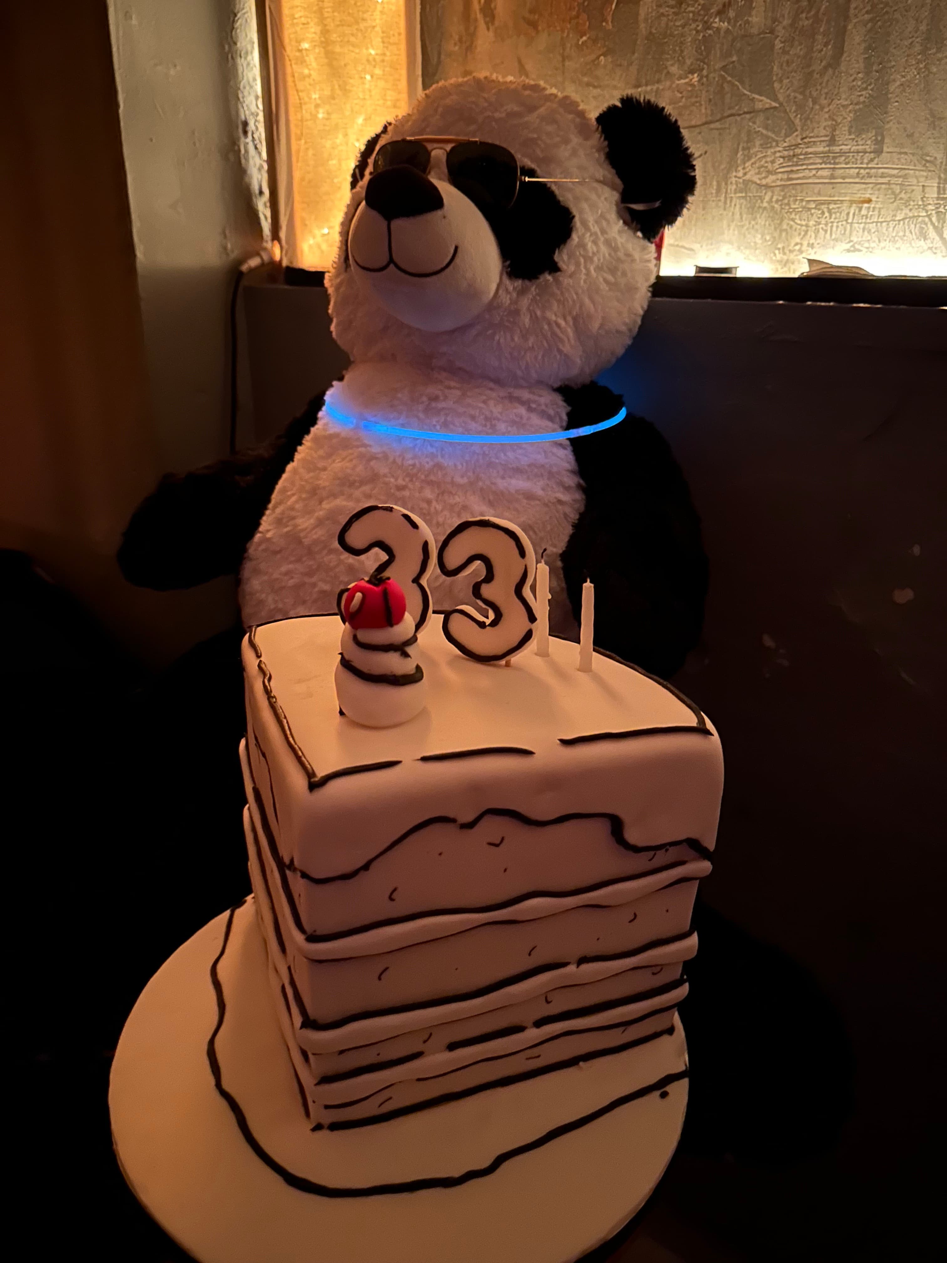 Stuffed panda with sunglasses next to a '33' birthday cake